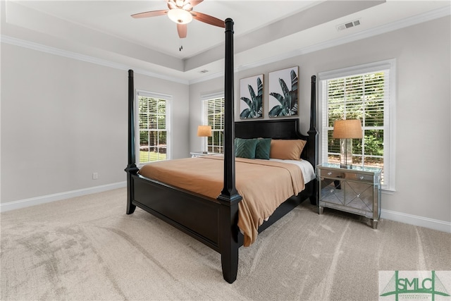 carpeted bedroom with a raised ceiling, ceiling fan, and ornamental molding