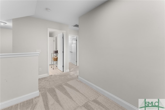 corridor with light colored carpet and vaulted ceiling