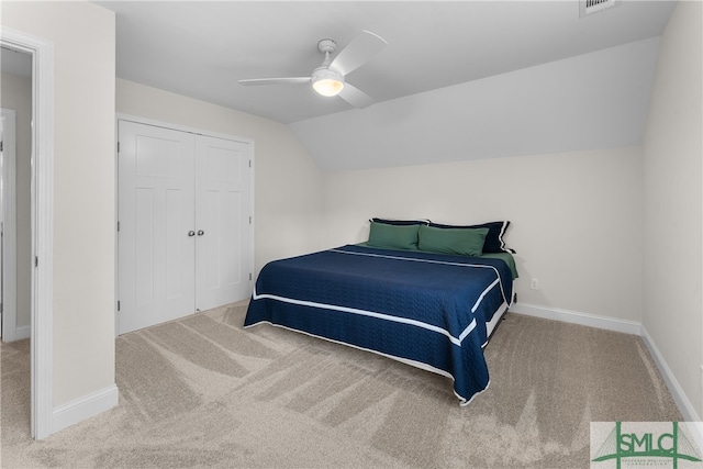 bedroom featuring a closet, ceiling fan, light carpet, and vaulted ceiling