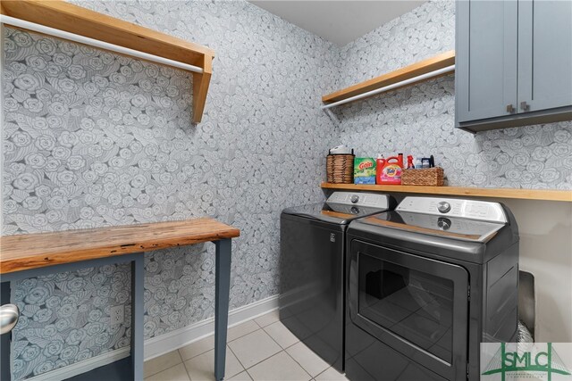 laundry room with cabinets, light tile patterned floors, and washer and clothes dryer