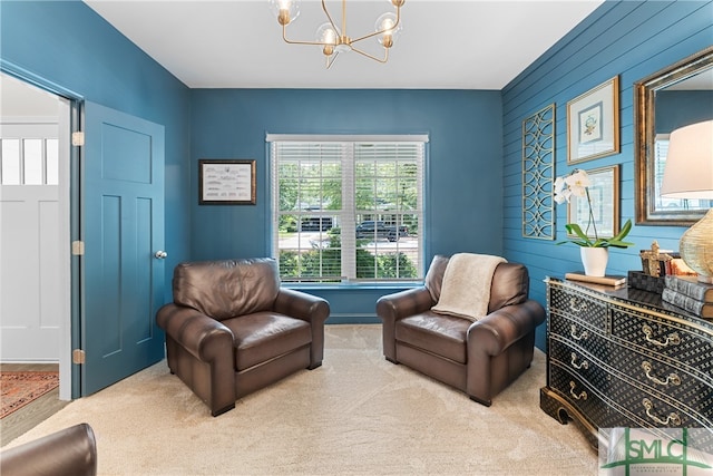 sitting room with wood walls, carpet flooring, and an inviting chandelier