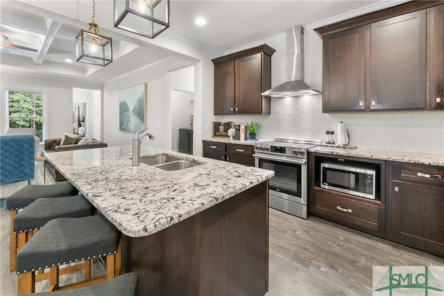 kitchen with coffered ceiling, light hardwood / wood-style flooring, stainless steel appliances, sink, and wall chimney exhaust hood