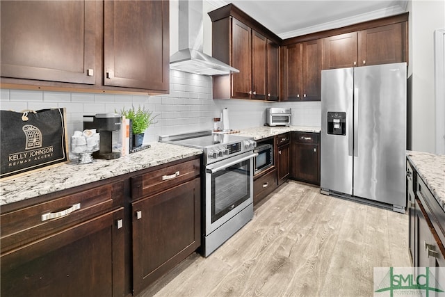 kitchen featuring light hardwood / wood-style floors, light stone counters, wall chimney exhaust hood, appliances with stainless steel finishes, and dark brown cabinetry