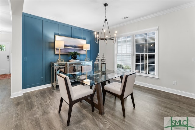 dining room featuring dark wood-type flooring, a notable chandelier, and ornamental molding