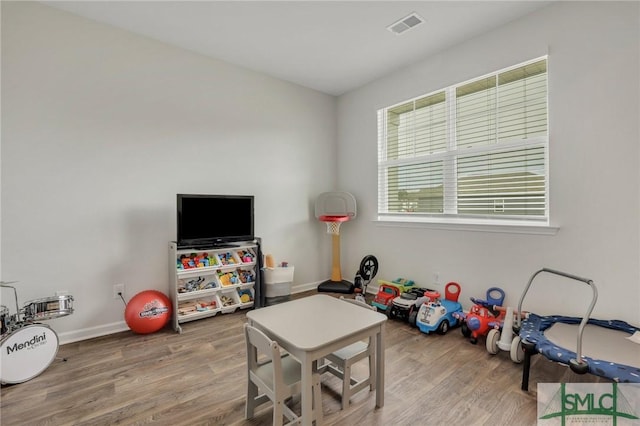 playroom with wood finished floors, visible vents, and baseboards