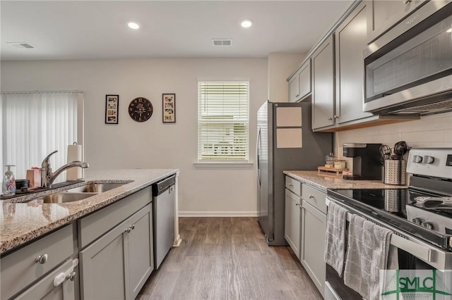 kitchen with visible vents, gray cabinetry, decorative backsplash, appliances with stainless steel finishes, and a sink