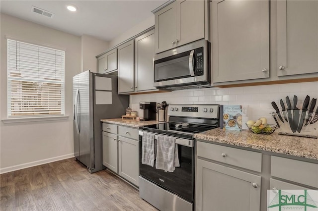 kitchen featuring decorative backsplash, visible vents, gray cabinets, and appliances with stainless steel finishes