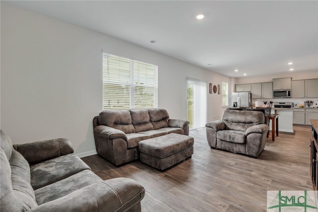 living area with recessed lighting, wood finished floors, visible vents, and baseboards