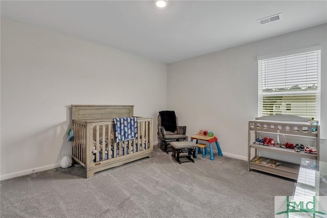 carpeted bedroom featuring a crib, baseboards, and visible vents