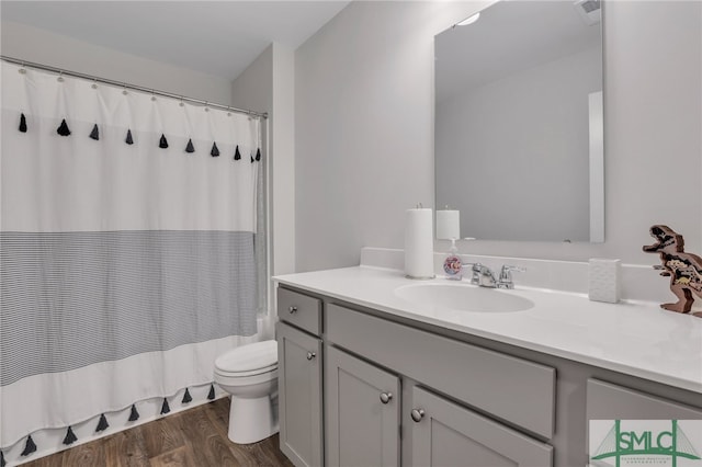 bathroom with vanity, toilet, wood finished floors, and shower / tub combo with curtain