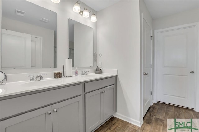 bathroom featuring double vanity, visible vents, wood finished floors, and a sink