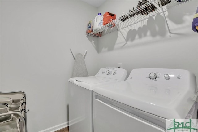 washroom featuring washer and clothes dryer, laundry area, and baseboards