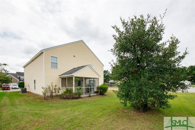 back of property featuring a sunroom, a lawn, and central AC unit