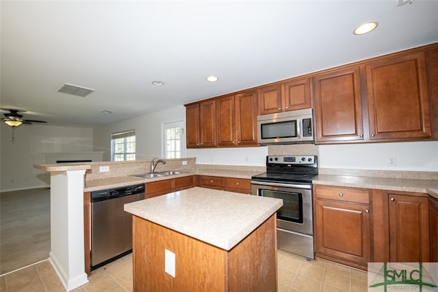 kitchen with a kitchen island, kitchen peninsula, stainless steel appliances, sink, and ceiling fan