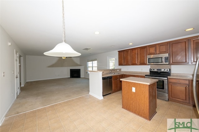 kitchen with kitchen peninsula, appliances with stainless steel finishes, sink, decorative light fixtures, and a center island