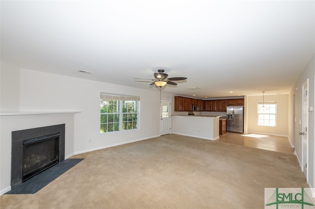 unfurnished living room featuring light carpet and ceiling fan