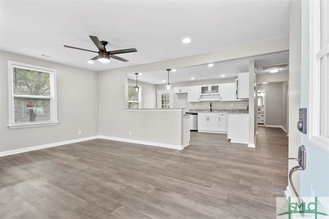 unfurnished living room with hardwood / wood-style floors, ceiling fan, and sink