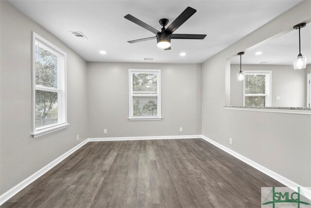 spare room featuring plenty of natural light, ceiling fan, and dark wood-type flooring