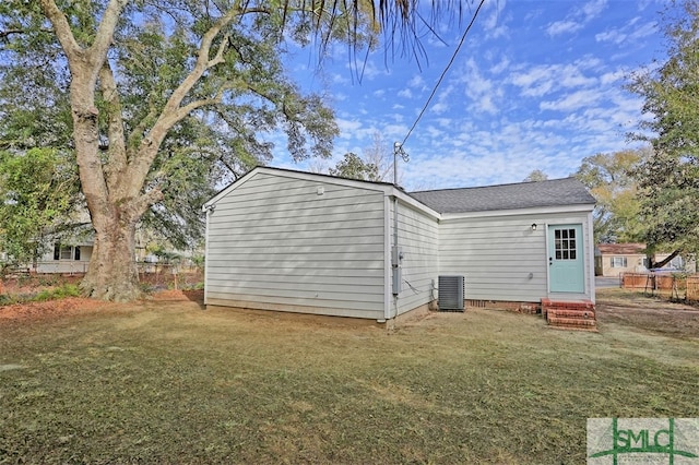 rear view of house featuring a lawn and central AC