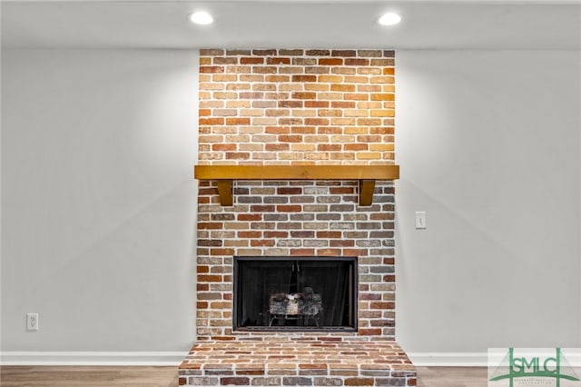 interior details featuring a brick fireplace and hardwood / wood-style flooring