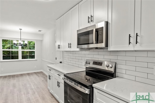 kitchen with light wood-type flooring, a notable chandelier, backsplash, stainless steel appliances, and white cabinets