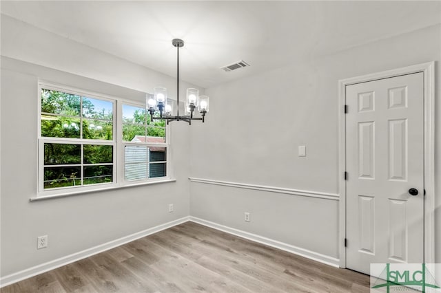 spare room featuring wood-type flooring and a chandelier