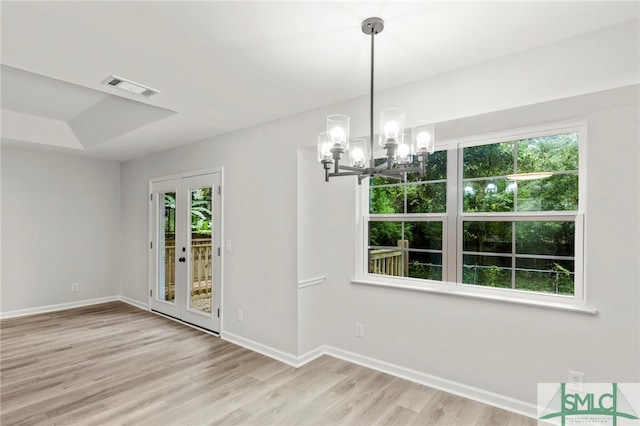 empty room with a healthy amount of sunlight, a chandelier, and light hardwood / wood-style floors