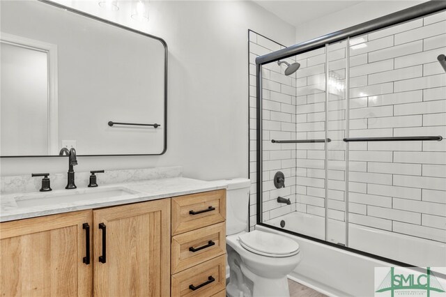 full bathroom featuring vanity, toilet, and combined bath / shower with glass door