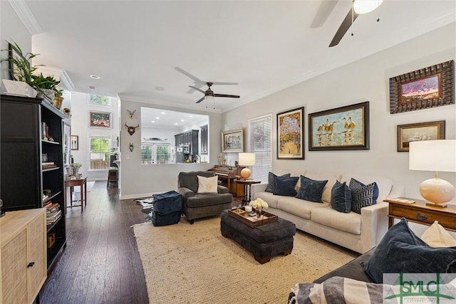 living area with ornamental molding, dark wood finished floors, a ceiling fan, and baseboards