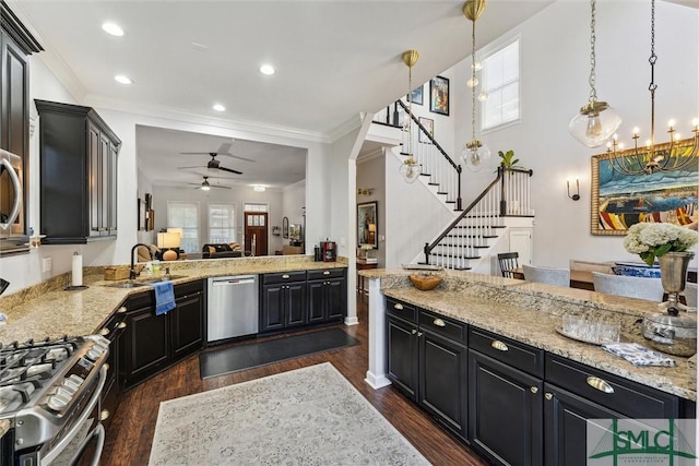 kitchen featuring stainless steel appliances, dark cabinetry, hanging light fixtures, and a peninsula