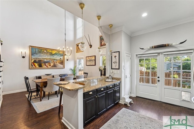 kitchen featuring dark wood-style floors, dark cabinetry, a kitchen bar, and decorative light fixtures