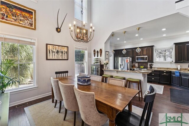 dining room featuring an inviting chandelier, a towering ceiling, crown molding, and dark hardwood / wood-style flooring