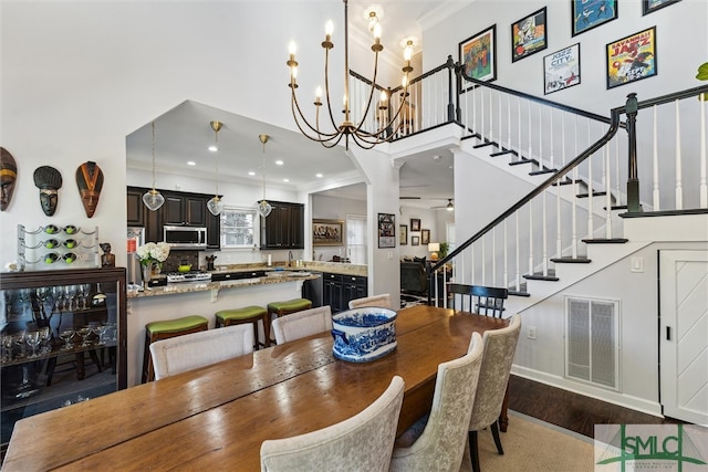 dining room with ornamental molding, hardwood / wood-style floors, sink, and a notable chandelier