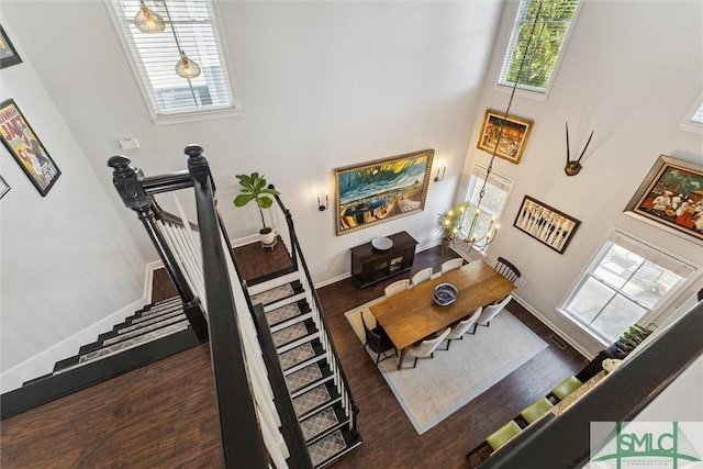 living area with a high ceiling, dark wood finished floors, and baseboards