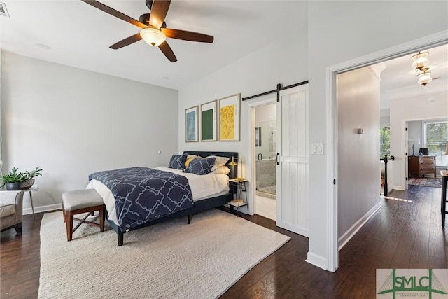 bedroom with ensuite bathroom, a barn door, visible vents, baseboards, and dark wood-style floors