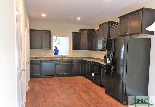 kitchen with light wood-type flooring, black appliances, dark brown cabinetry, and sink