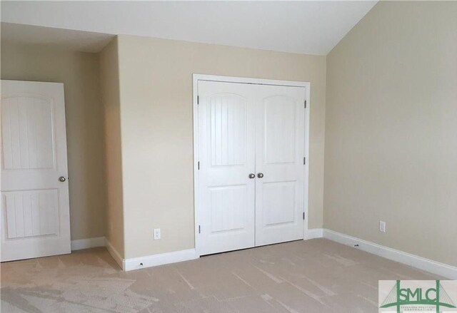 unfurnished bedroom featuring light colored carpet and a closet