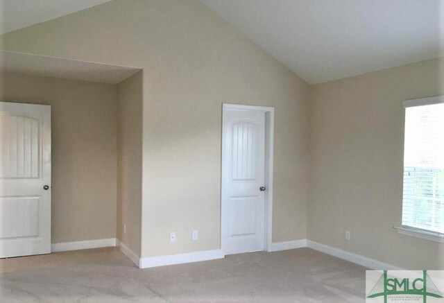 carpeted empty room featuring vaulted ceiling