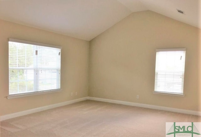 carpeted spare room with plenty of natural light and vaulted ceiling