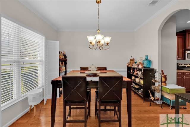 dining space featuring light wood-type flooring, a chandelier, and ornamental molding