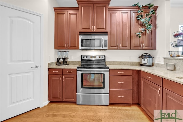 kitchen featuring light stone counters, stainless steel appliances, and light hardwood / wood-style floors