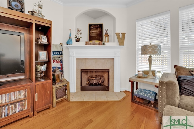 living room featuring a tile fireplace, hardwood / wood-style flooring, and crown molding