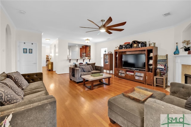 living room with crown molding, light hardwood / wood-style flooring, and ceiling fan