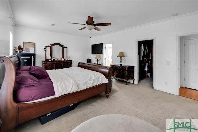 carpeted bedroom with a walk in closet, ceiling fan, a closet, and ornamental molding