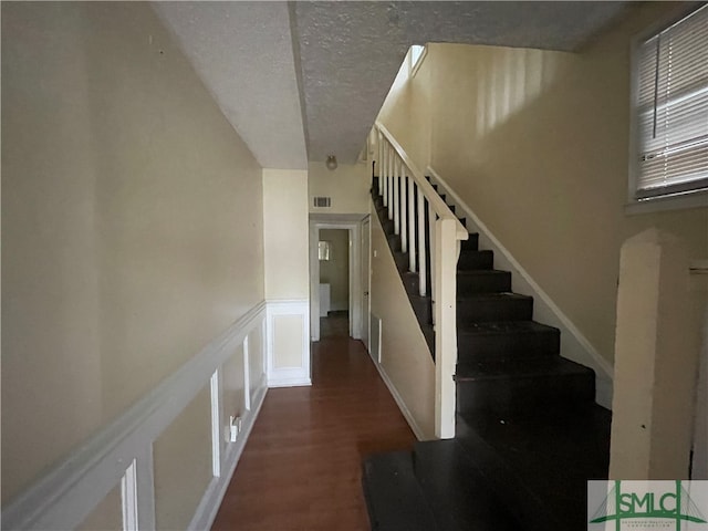 stairs with a textured ceiling and hardwood / wood-style floors