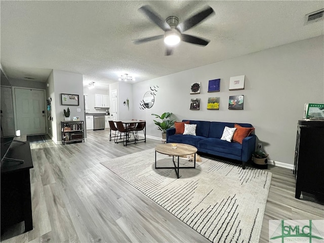 living room featuring ceiling fan, a textured ceiling, and light hardwood / wood-style flooring