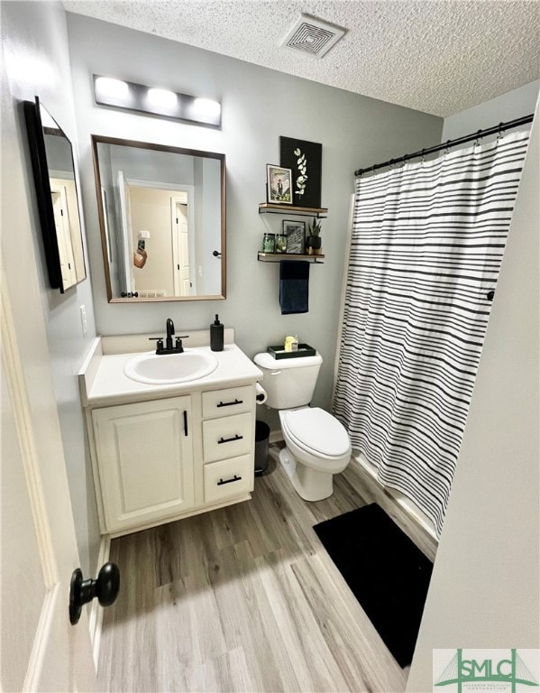 bathroom featuring a textured ceiling, vanity, toilet, and hardwood / wood-style flooring