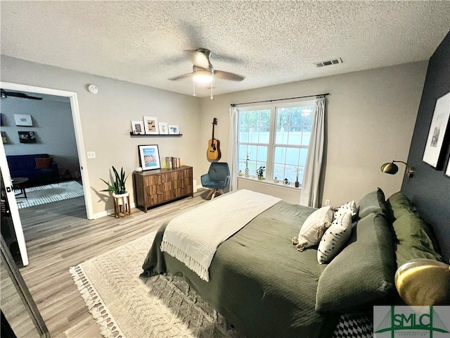 bedroom with a textured ceiling, light hardwood / wood-style floors, and ceiling fan