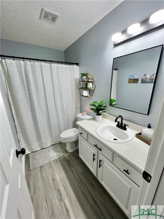 bathroom featuring vanity, a textured ceiling, hardwood / wood-style floors, and toilet