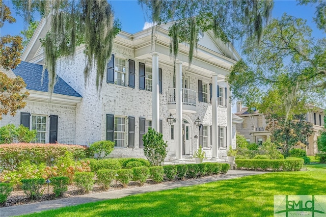 view of front of property featuring a balcony and a front lawn